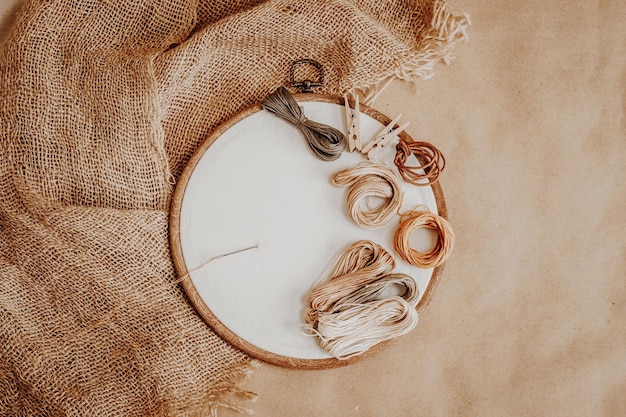 Photo hoop with white cotton fabric and threads on the background of burlap