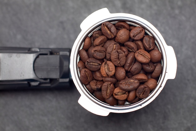 Hoorn met koffiebonen. Koffiemachine Filterhouder met koffiebonen op zwart leisteen bord.