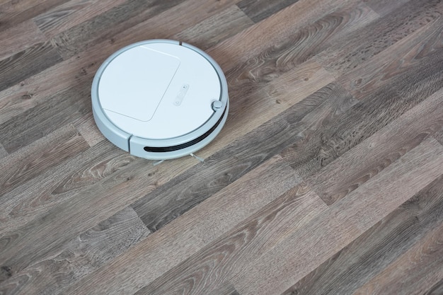 Hoovering floor with modern robotic vacuum cleaner indoors, closeup