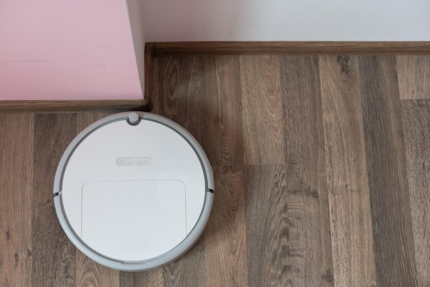 hoovering floor with modern robotic vacuum cleaner indoors, closeup