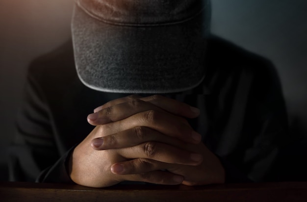 Hope and Religion Concept, Mysterious Hopeful Man in hat making Hands to Praying in the da