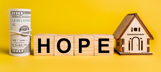 Hope con modello di casa in miniatura e denaro su sfondo giallo. il concetto di affari, finanza, credito, tasse, immobili, casa, alloggio