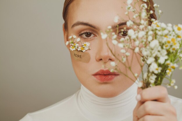 Hope Young woman with flowers and Hope inscription on adhesive plaster female face close up