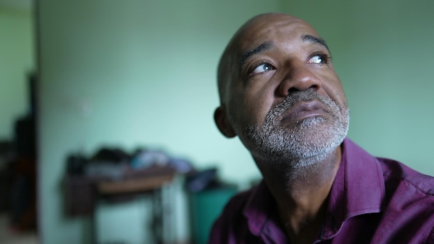 A hopeful black senior man smiling looking out window having\
faith