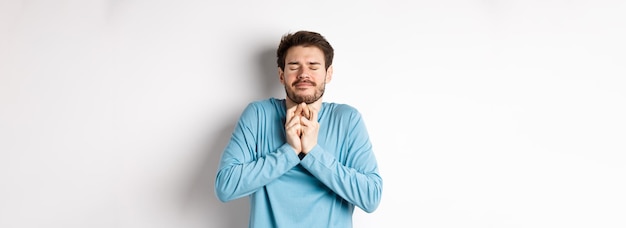 Hopeful caucasian guy in sweatshirt cross fingers for good luck young man making wish praying with e