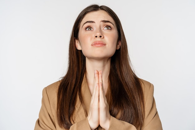 Hopeful corporate woman, student praying, begging god, looking up and pleading, standing over white background