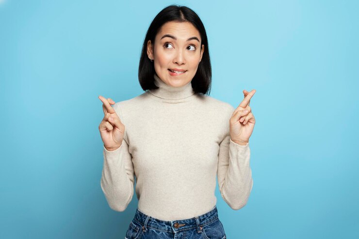 Photo 幸運のために指を交差させる若い年齢の有望な神経質な茶色の髪の女性