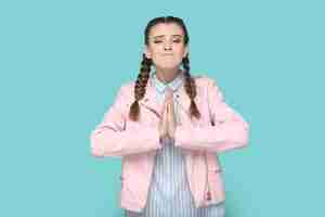 Photo hopeful teenager girl with braids keeps hand in praying gesture pleading asking to forgive