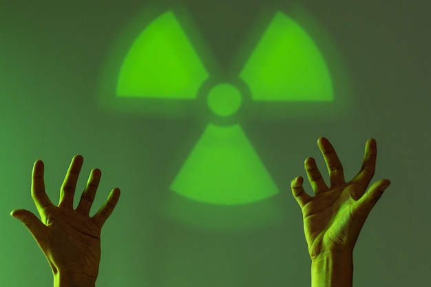 Hopeless situation.The male hands touches the sign of radiation hazard. Green background. Copy space.