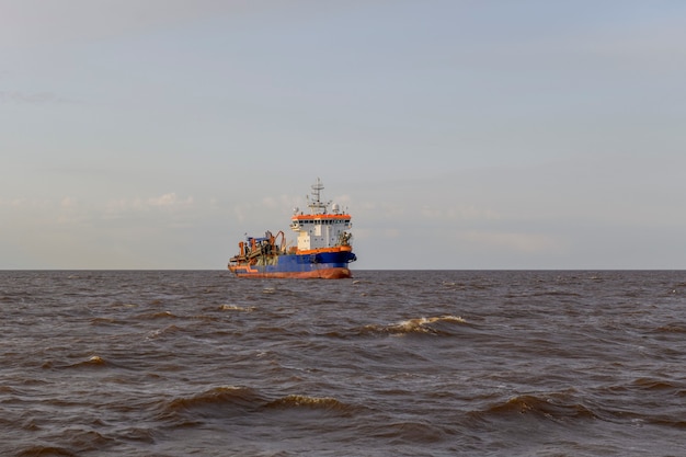 Hopper dredger at sea. Vessel engaged in dredging. Construction Marine offshore works. Dam building, crane, barge, dredger.