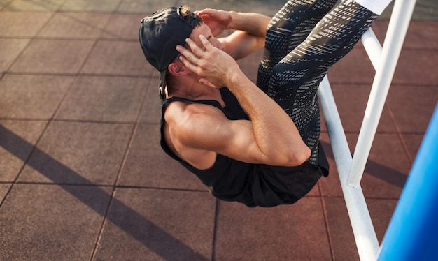 Foto horizontaal beeld van een jonge fitnessman die maagtraining doet op de horizontale balk buitenshuis