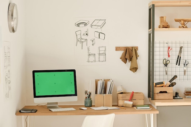 Horizontaal beeld van werkplek met computer op tafel en blauwdrukken aan de muur in werkplaats