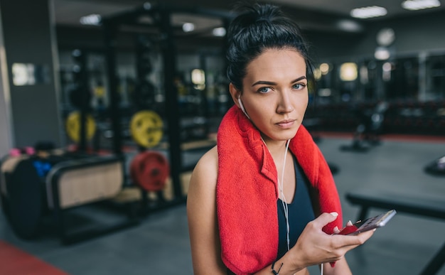 Horizontaal geschoten portret van een mooie jonge vrouw die naar muziek luistert vanaf haar smartphone met een pauze na een training in de sportschool Mensen technologie fitness en sport concept