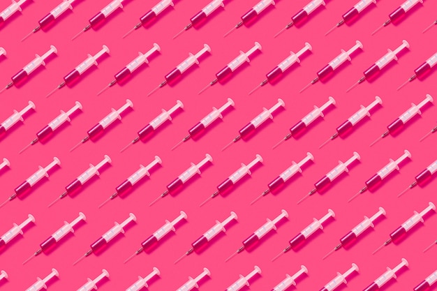 Horizontaal gezondheidszorgpatroon van steriele plastic wegwerpnaalden met roze vloeistof of vaccin