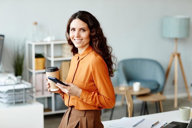 Horizontaal medium portret van charmante blanke vrouw met lang golvend haar met kopje koffie sur