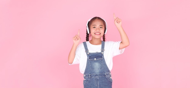 Horizontaal portret van een schattig, mooi Aziatisch klein meisje dat naar muziek luistert met een hoofdtelefoon die op de achtergrond is geïsoleerd