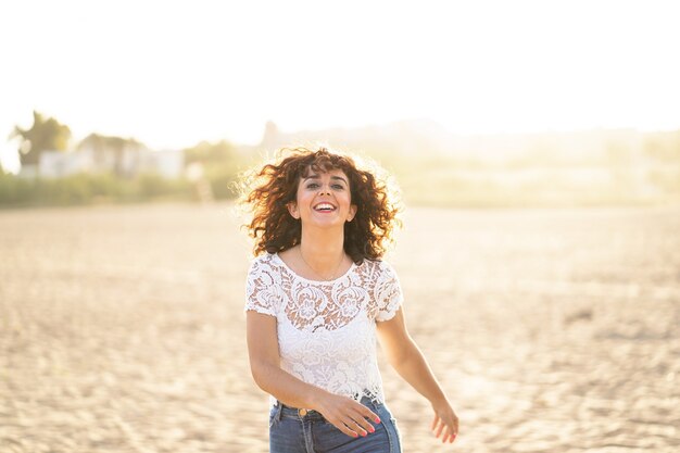 Horizontaal portret van een vrouw die bij zonsondergang op het strand loopt. Geluk zomer levensstijl concept.