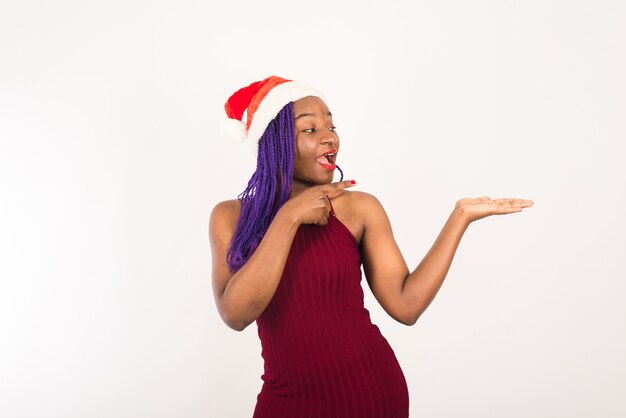 Horizontaal portret van gelukkig donker gevild gemengd ras vrouwelijk model in de kerstman hoed