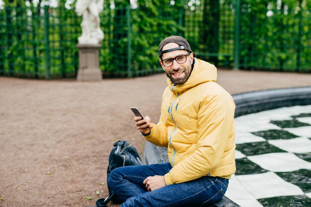 Horizontaal portret van het gebaarde hipstermannetje die opzij met verrukkelijke uitdrukking kijken terwijl het zitten