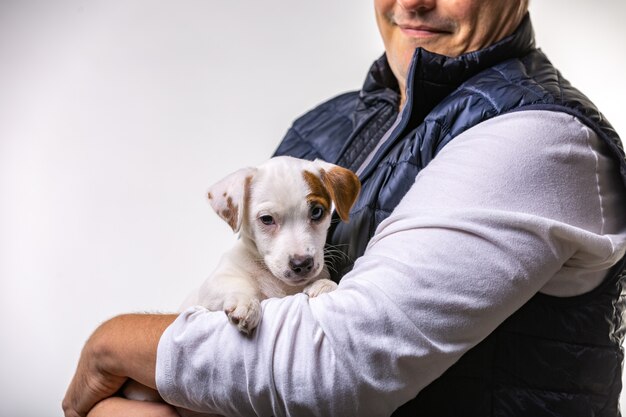 Horizontaal portret van knappe vrolijke man houdt jack russell terrier vast, heeft een blije uitdrukking