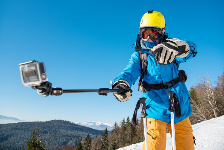 Horizontaal schot van een mannelijke skiër die pret heeft die in openlucht een selfie met actiecamera neemt op een monopod