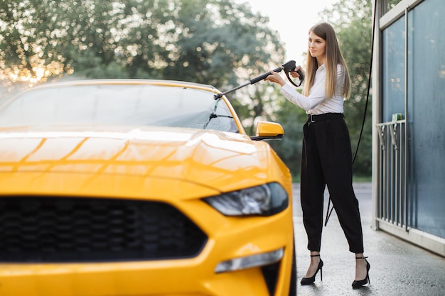 Horizontaal schot van jonge blanke aantrekkelijke vrouw draagt een zakelijke look die haar luxe auto wast