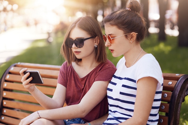 Horizontaal schot van mooie twee vrouwelijke studenten in casual zomer kleding