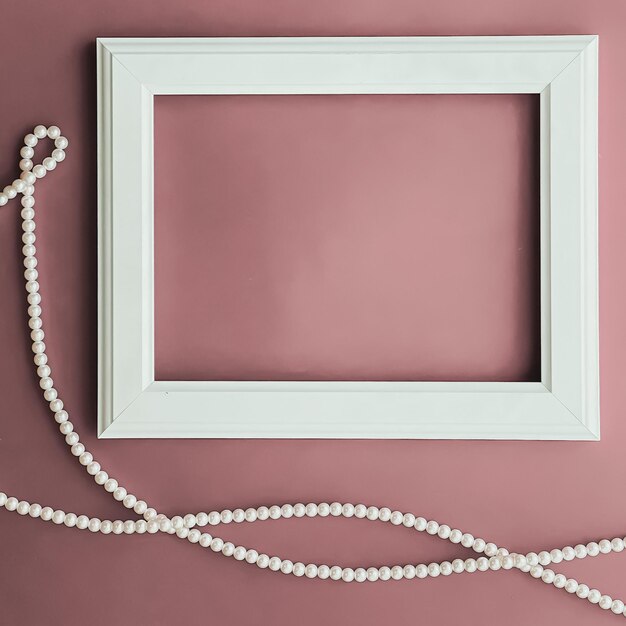 Photo horizontal art frame and pearl jewellery on blush pink background as flatlay design artwork print or photo album