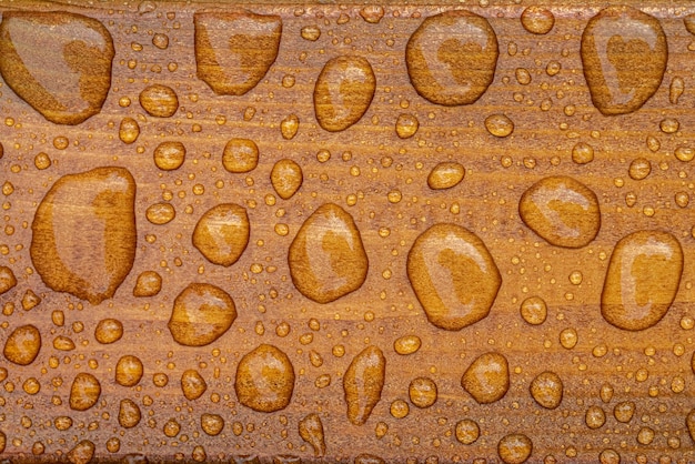 Horizontal background of lacquered burnt wood texture with shiny water drops from the rain wet wooden planks