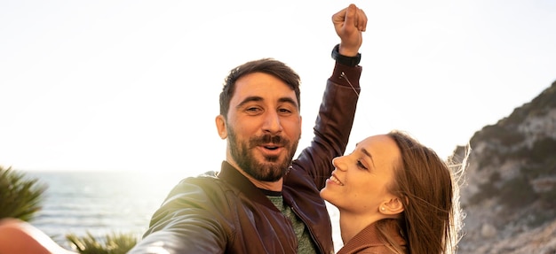 Banner orizzontale o intestazione con giovane coppia hipster che si diverte a fare un selfie ritratto contro un bellissimo panorama al tramonto fidanzato e fidanzata innamorati che sorridono insieme alla telecamera