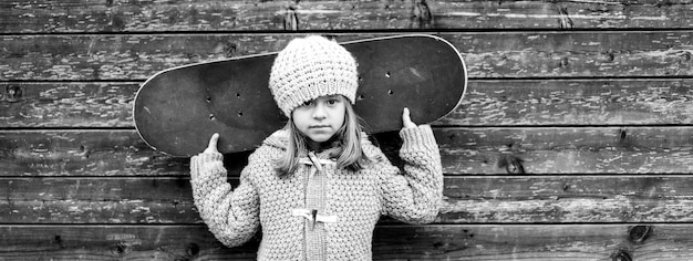 Horizontal banner or header with portrait of child girl skateboarder in wool winter clothes