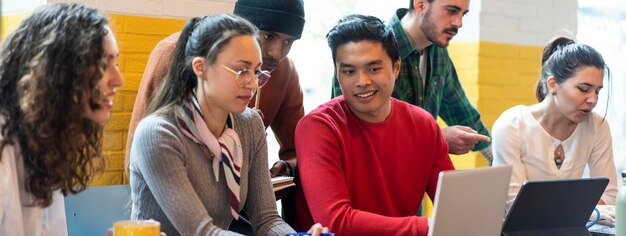 Horizontal banner or header with young coworkers multiethnic team planning a new startup People working on a new project in creative coworking office Bright filter with focus on asian man face