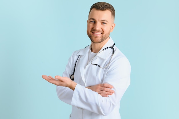 Banner orizzontale di giovane medico maschio sorridente che mostra e presenta qualcosa con la mano isolata su sfondo blu con spazio per la copia sul lato sinistro