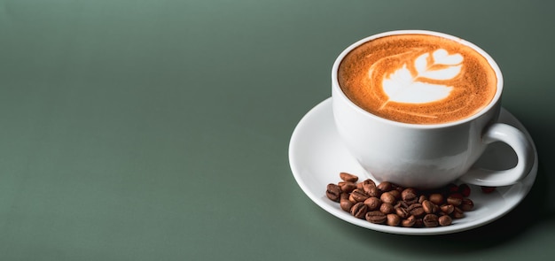 Horizontal banner with cup of coffee and coffee beans on green\
background top view copy spacecoffee latte topview