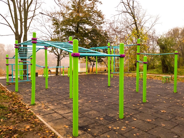 안개 낀 가을 아침 도시 공원의 빈 운동장에서 운동할 수 있는 수평 막대와 현대적인 스포츠 장비