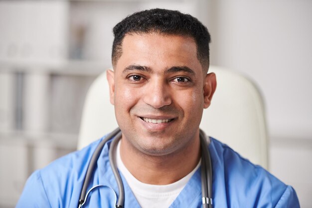 Horizontal closeup portrait shot of happy young adult MiddleEastern male medical worker looking at camera smiling