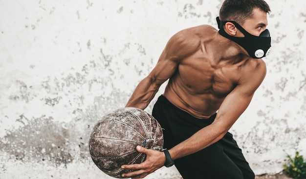 운동을 하는 셔츠를 입지 않은 스포츠맨이 광고를 위한 야외 복사 공간에서 마스크를 쓰고 운동을 하는 피트니스 근육질 남성의 수평 이미지