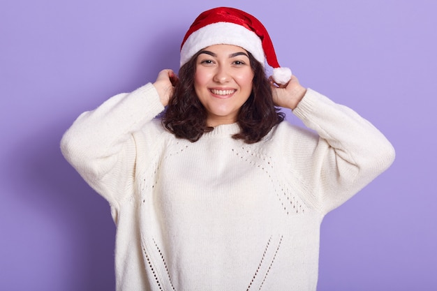 Horizontal indoor picture of cheerful adorable young girl with dark curly hair