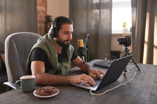 Horizontal medium portrait of modern bearded young middle eastern influencer sitting alone in loft r