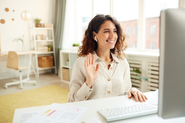 Horizontal medium portrait of young adult female manager taking part in online meeting while staying home