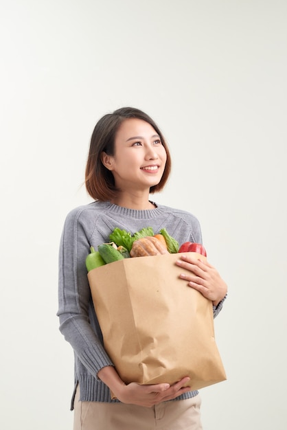 Immagine a colori con orientamento orizzontale di una donna che tiene in mano un sacchetto di carta traboccante di verdure / aggiunta di verdure alla dieta