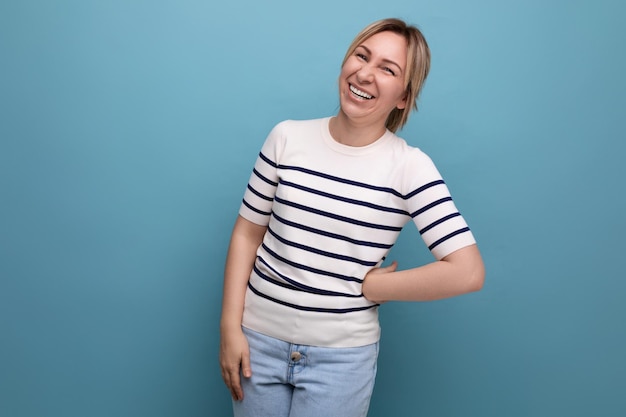 Horizontal photo of ardent energetic happy blonde woman in casual outfit smiling cute on blue