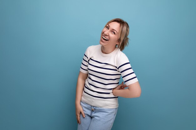 Horizontal photo of bright cheerful happy blonde woman in casual outfit on blue background with copy