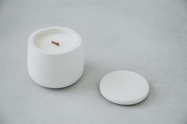 Horizontal Photo of Candle in Plaster Concrete Candlestick and Lid Next it on Gray Concrete Plane