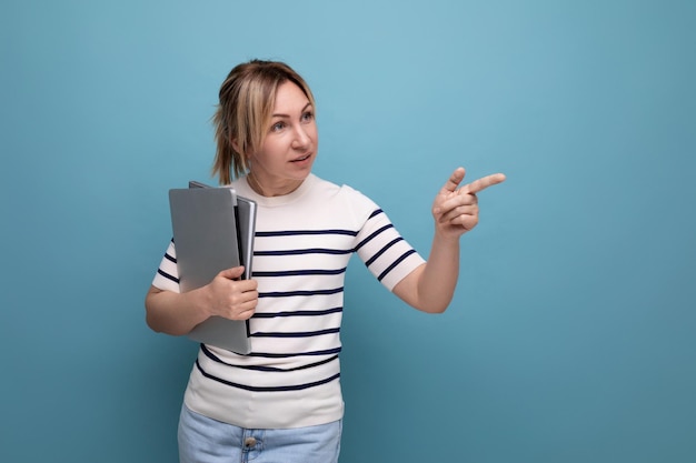 Horizontal photo of a charming woman in a casual striped sweater with a laptop computer laptop in