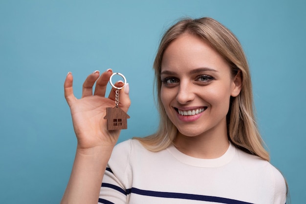 Horizontal photo of a happy young woman who bought an apartment in a mortgage on a blue isolated