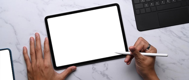 Horizontal photo of woman holding stylus pen writing on digital tablet on marble table.