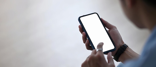 Horizontal photo of young man holding mobile phone with empty screen. Blank screen for your advertising text.