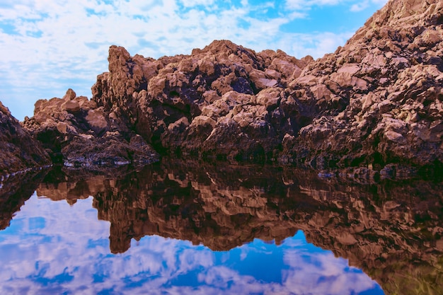 Horizontal picture of rocks and their reflection in the sea