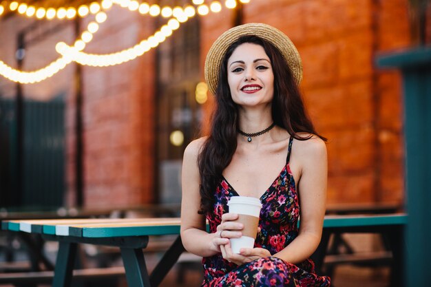 Horizontal portrait of beautiful female with make-up dressed in straw hat and dress